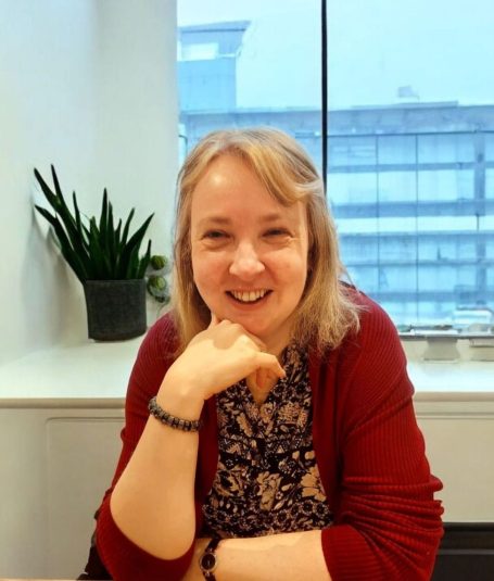 A portrait image of the founder of Lynda Stone Bookkeeping, Lynda Stone. She is sat within an office building, smiling at the camera.